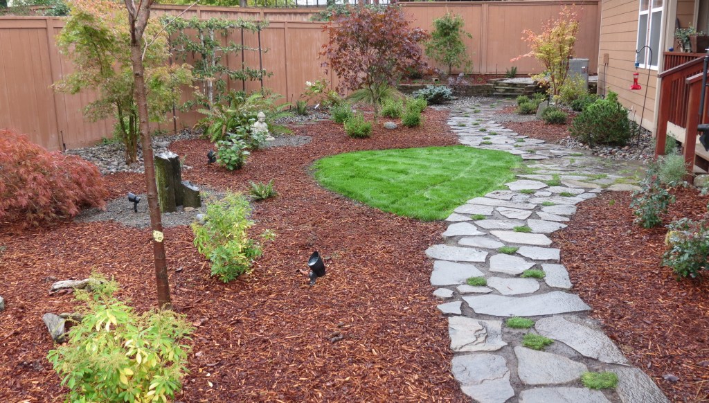 Well-kept garden beds, lawn and stone path maintained by Artisan Landscapes